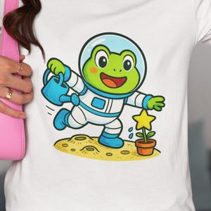 Astronaut Frog Watering Star Plant Tee - Cute Space Frog Cartoon Unisex T-Shirt for Adults, Youth & Toddlers, Kawaii Gift for Science Lovers