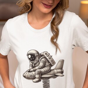 Unisex T-Shirt with Astronaut Sitting on a Spring Airplane Ride, Space Adventure Novelty Tee, Sci-Fi Enthusiasts Top, Unique Cosmic Shirt