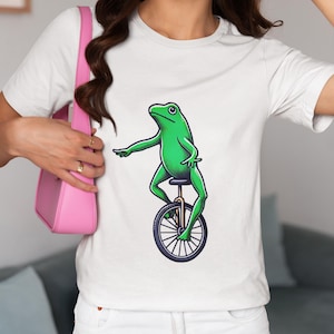 Whimsical Frog Riding a Unicycle Graphic Unisex T-Shirt, Fun Amphibian Novelty Tee Shirt for Frog Lovers, Unique Froggy Bicycle Top Design