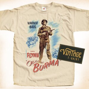 Puede incluir: Camiseta color crema con un diseño de cartel de película vintage. El cartel representa a un soldado sosteniendo un arma, con el texto "WARNER BROS." y "OBJECTIVE BURMA." También hay una etiqueta "VINTAGE T-SHIRT".