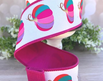Könnte beinhalten: Eine Rolle weißes Band mit einem sich wiederholenden Muster aus bunten Kürbissen in Rot-, Türkis-, Pink- und Violetttönen mit goldenen Stielen. Das Band hat einen leuchtend fuchsiafarbenen, genähten Rand und ist auf eine Spule gewickelt.