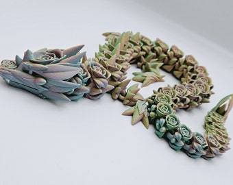 Könnte beinhalten: Eine detaillierte, bewegliche Drachenskulptur in Pastellfarben. Der Drachenkopf und -körper sind mit sukkulentenartigen Details in Blau-, Grün- und Lilatönen verziert. Ein einzigartiger Dekorationsartikel.