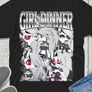 May include: A black short-sleeve t-shirt featuring the text GIRL DINNER in a metallic font above a collage of five illustrations of a grey wolf character with red eyes, wearing a spiked collar, set against a background of grey smoke.