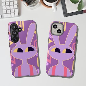 Op de afbeelding: Twee telefoonhoesjes met een paars cartoon konijn ontwerp. Het konijn heeft grote oren, gele ogen en een roze en rood gestreepte torso. De achtergrond is een geometrisch patroon van paarse, gele en roze vormen. Eén hoesje heeft drie cameralenzen, de andere heeft er twee.