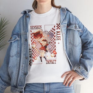 May include: White t-shirt featuring a graphic of a character from Genshin Impact, with the text "GENSHIN IMPACT" and "KLEE". The design includes a red and white checkered pattern and cartoon imagery. The shirt is worn with a denim jacket.