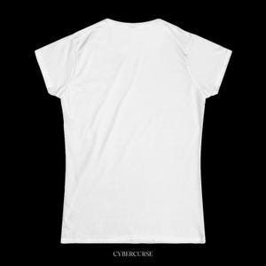May include: A white t-shirt with a crew neck and short sleeves. The text "CYBERCURSE" is printed in a sans-serif font at the bottom of the shirt. The shirt is made of a soft, likely cotton, material.