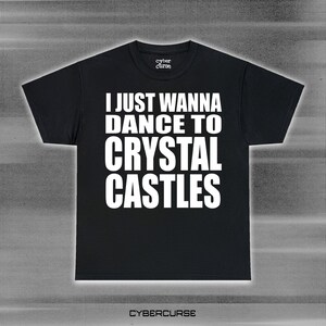 May include: Black t-shirt with white text that reads "I just wanna dance to Crystal Castles". The text is centered on the shirt. The shirt is a standard t-shirt style with short sleeves and a crew neck.