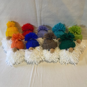 May include: A collection of ten handmade gnome ornaments with white pom-pom beards and colorful knit hats. The hats are yellow, red, blue, purple, brown, green, and teal.