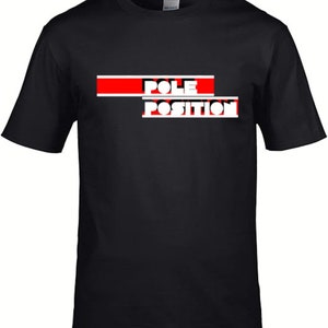 Puede incluir: Camiseta negra con un gráfico rojo y blanco que dice "POLE POSITION" en letras blancas en negrita.