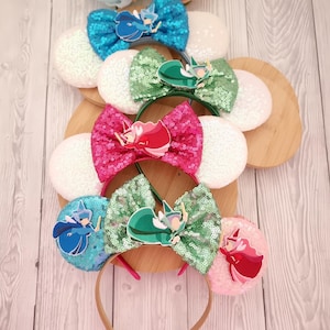 Può includere: Una collezione di cerchietti decorativi con fiocchi di paillettes e abbellimenti di personaggi. I cerchietti presentano orecchie di paillettes bianche e fiocchi in verde acqua, verde e rosa. Ogni fiocco ha un design di personaggio.