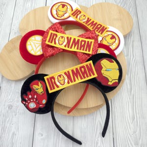 May include: A selection of Iron Man-themed headbands in black, red, and white. Each headband displays the Iron Man logo and the word "Ironman" in yellow and red. One headband has a sequined bow.
