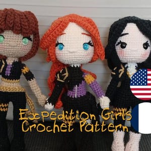 May include: Three handmade crochet dolls with different hair colors: brown, red, and black. Each doll wears a black outfit with gold and purple accents. The dolls have detailed facial features and are standing together. The text "Expedition Girls Crochet Pattern" is visible.