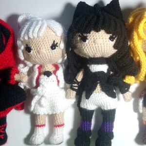 May include: Four handmade crochet dolls, each with unique outfits and hairstyles. The dolls feature black, white, red, and yellow hair, and are dressed in detailed, colorful outfits. The dolls are approximately 6 inches tall.