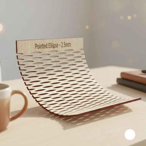 Puede incluir: Una pieza decorativa de madera curvada con un dise&ntilde;o de celos&iacute;a y el texto "Pointed Ellipse - 2.5mm". La pieza es de color marr&oacute;n claro con bordes rojos y se encuentra sobre una superficie clara. Una taza de caf&eacute; y una planta suculenta est&aacute;n en el fondo.