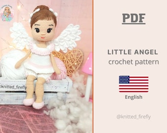 May include: A crocheted doll in the shape of an angel, wearing a white and pink dress, white shorts, and pink shoes. The doll has white wings and a halo. The image includes the text "LITTLE ANGEL crochet pattern" and the American flag.