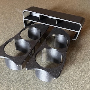 May include: A set of three metallic gray automotive parts. Two parts have two circular openings, and the third part is a rectangular housing with two compartments. The parts are made of a textured metal.