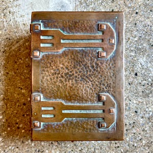 May include: A hammered copper box with a geometric design. The box has a textured surface and a green patina.
