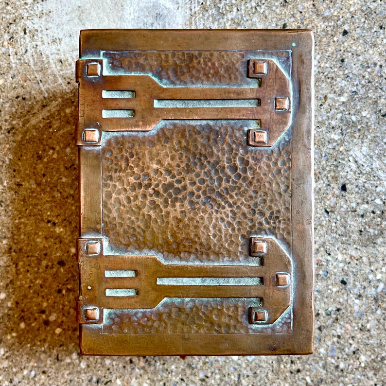 May include: A hammered copper box with a geometric design. The box has a textured surface and a green patina.