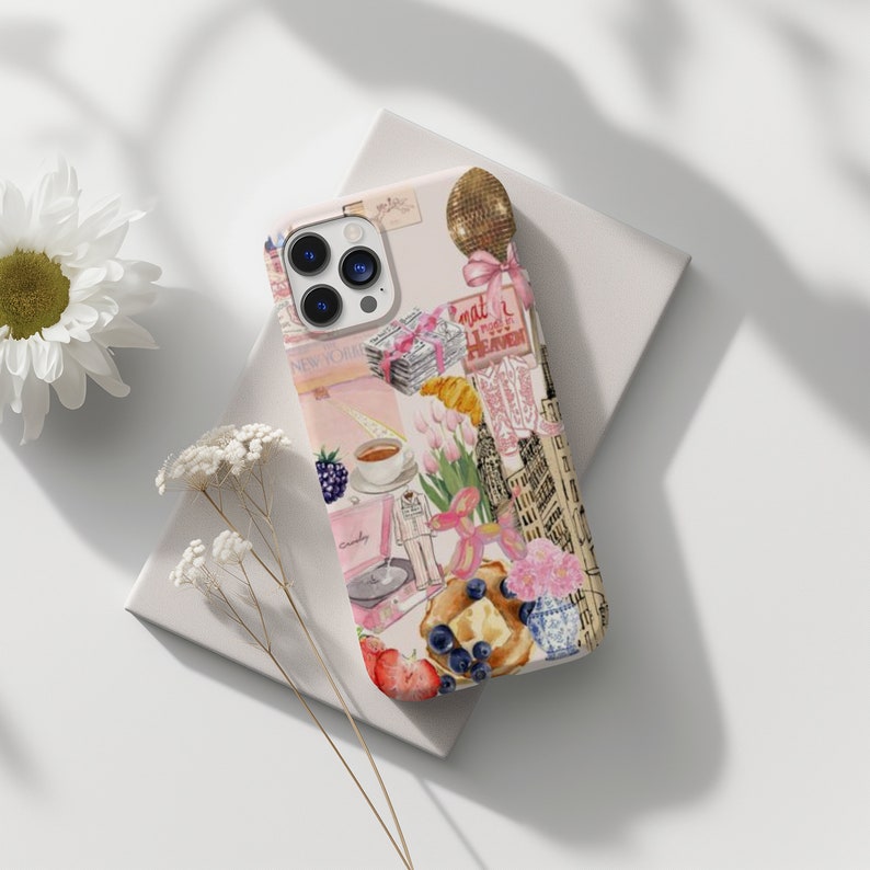 Op de afbeelding: Een roze en witte iPhone-hoes met een collage van afbeeldingen, waaronder een kopje koffie, een croissant, een ballon en een gebouw. De tekst "What a Sweet Heaven" is zichtbaar op de hoes.
