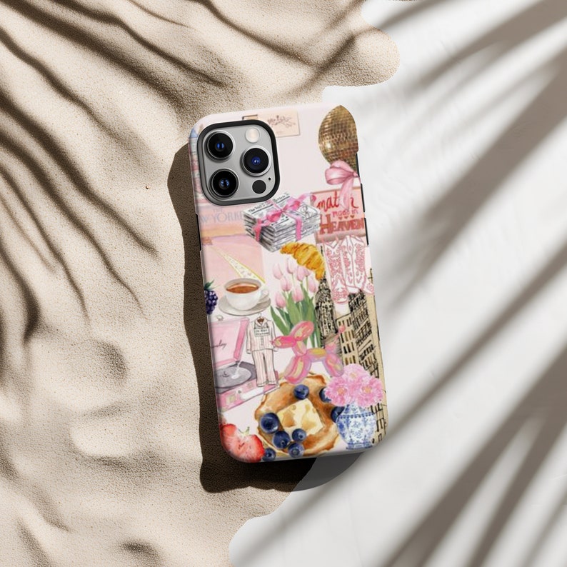 Op de afbeelding: Een roze en witte iPhone-hoes met een collage van afbeeldingen, waaronder een croissant, bloemen, een kopje koffie, een platenspeler en een gebouw. De tekst "What a mess! Heaven" is zichtbaar op de hoes.