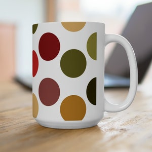 May include: White ceramic mug with a polka dot pattern in red, green, brown, and gold.