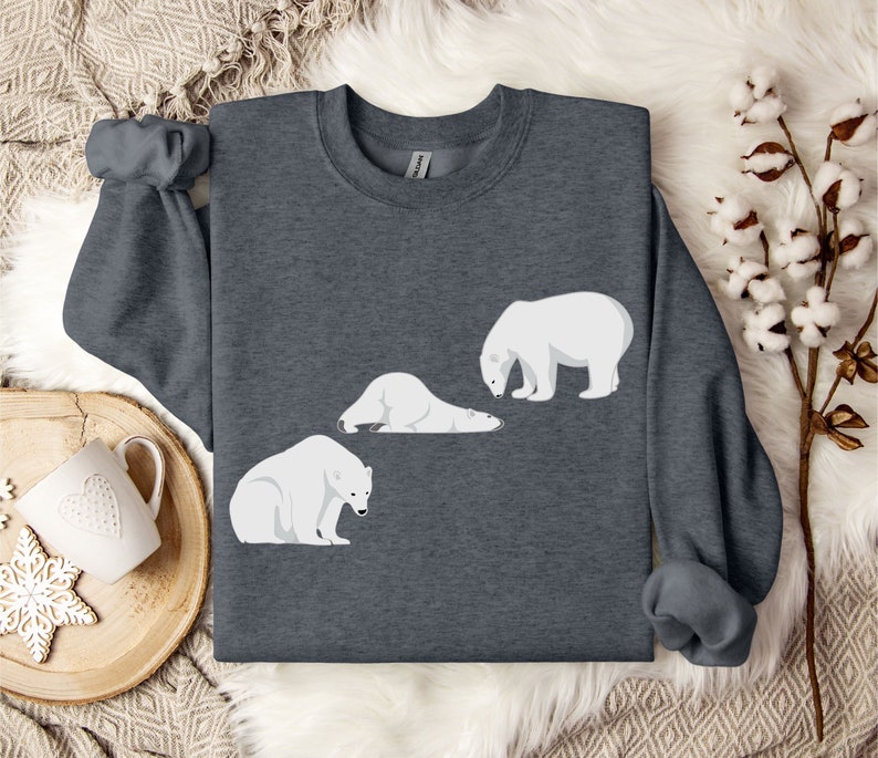 Peut inclure: Un sweat-shirt gris fonc&eacute; avec un motif blanc de trois ours polaires. Deux des ours sont couch&eacute;s et un est debout.