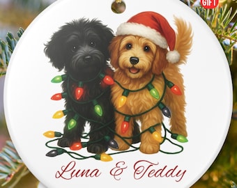 May include: A white ceramic Christmas ornament featuring two dogs, one black and one golden, adorned with colorful Christmas lights. The golden dog wears a Santa hat. The ornament is personalized with the names "Luna & Teddy" and the year "2025". The text "PERSONALIZED GIFT" is also visible.