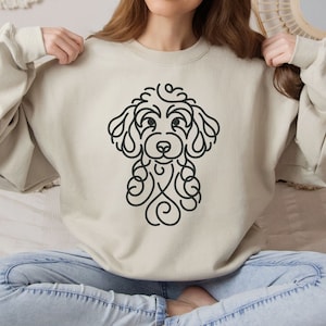 May include: A beige sweatshirt with a black line drawing of a poodle on the front.