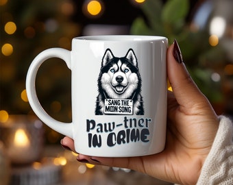 May include: White ceramic mug with a black and white husky dog illustration. The dog is holding a sign that says "Sang the Moon Song". The mug also has the text "Paw-tner in Crime" in blue and black lettering.