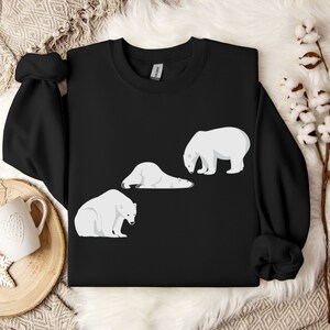 Peut inclure: Sweat-shirt noir avec un motif de trois ours polaires blancs. Deux ours sont couch&eacute;s et un est debout.