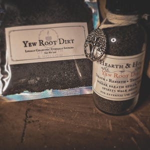 May include: A glass bottle and a bag filled with dark material, labelled "Yew Root Dirt." The bottle has a silver tree of life charm and a label with text. The bag is labelled "Hearth & Hollow."