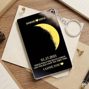 Può includere: Un portachiavi rettangolare nero con una grafica a mezzaluna gialla. Il testo recita SAMUEL CUORE SOFIA, 01.17.2021, THIS IS WHAT THE MOON LOOKED LIKE THE DAY I SAW YOU FIRST TIME, e I LOVE YOU con un piccolo simbolo di cuore giallo.