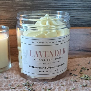 May include: A clear plastic jar filled with pale yellow whipped body butter. The label reads "Lavender Whipped Body Butter" and "All Natural and Organic Ingredients." The net weight is 113 grams.