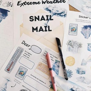 May include: A collection of stationery items with an "Extreme Weather" theme. Includes printed sheets with fill-in-the-blank prompts, stickers, and pens. The phrase "Snail Mail" is prominently displayed. A pink and a black pen are visible.