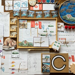 May include: A collection of educational materials for children featuring a Canadian theme. The materials include worksheets, flashcards, and manipulatives with images of Canadian landmarks, animals, and symbols. The materials are designed to teach children about Canada's geography, history, and culture.