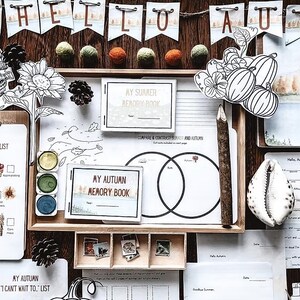 May include: A flat lay of autumn-themed stationery and decorations. Includes a clipboard with an "Autumn Bucket List", watercolor paints, and a banner that says "Hello Autumn". There are also decorative elements like pinecones and felt balls.