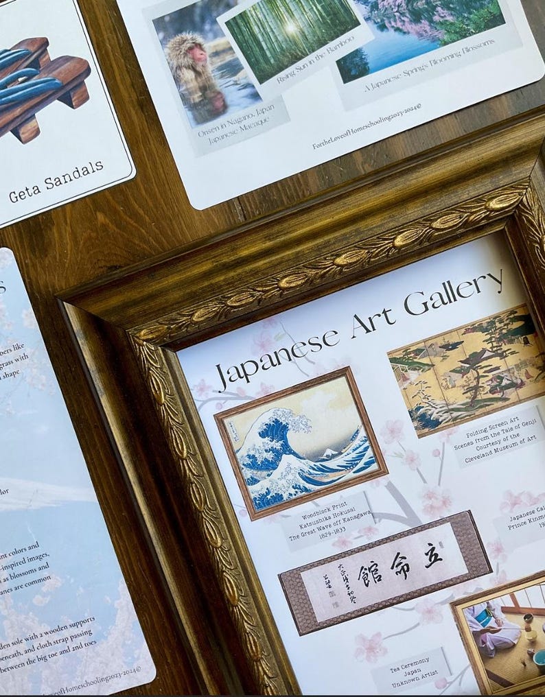 May include: A framed print of a Japanese woodblock print titled 'The Great Wave of Kanagawa' by Katsushika Hokusai. The print is surrounded by other Japanese art prints and a small piece of paper with Japanese text that reads '館命立'. The frame is gold and has a decorative design. The background is a light pink with a floral pattern.