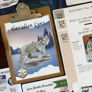 May include: A brown clipboard with a white paper insert featuring a drawing of a Canadian Lynx in a snowy landscape. The text "Canadian Lynx" is printed in black at the top of the page. The clipboard is on a blue surface.