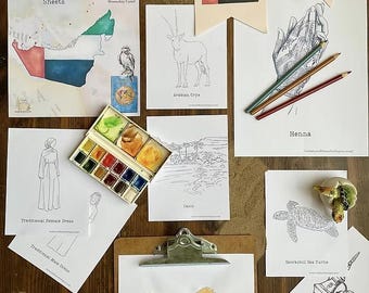 Pode incluir: Uma coleção de folhas para colorir e materiais de arte em uma superfície de madeira. As folhas apresentam ilustrações de animais árabes, roupas tradicionais e dos Emirados Árabes Unidos. Uma paleta de aquarela e lápis de cor também estão presentes.