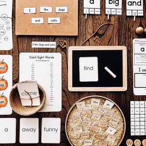 Peut inclure: Matériel pédagogique pour l'apprentissage précoce, comprenant des cartes de mots courants, des cartes flash sur le thème des pommes et un petit tableau noir avec de la craie. L'image présente les mots "I like dogs and cats" et "find". Les articles sont disposés sur une surface en bois.