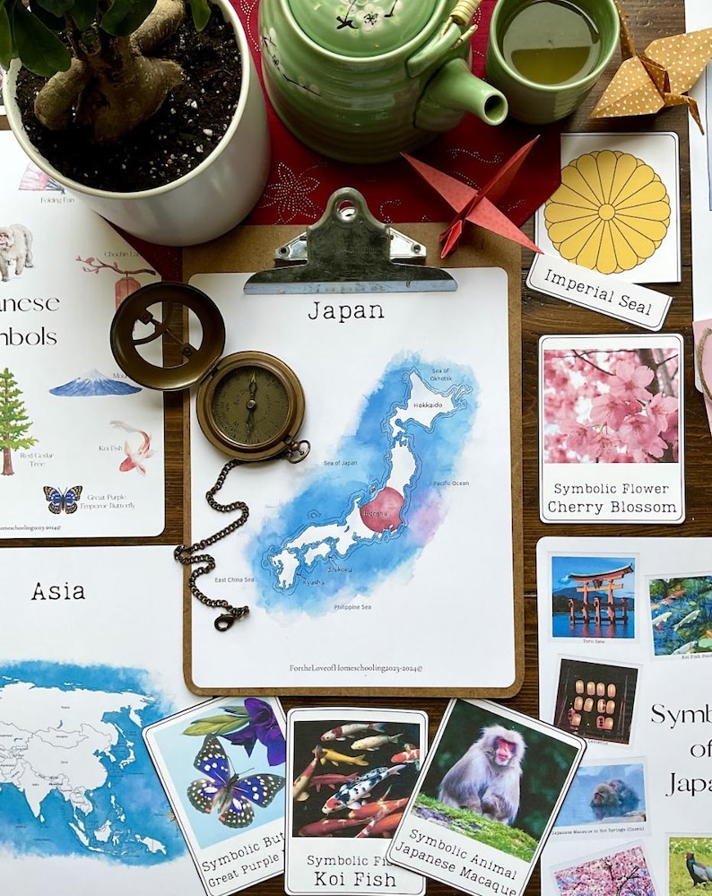 May include: A watercolor illustration of Japan with a blue and white color scheme. The illustration is surrounded by flashcards with images and text about Japan. The flashcards include images of a cherry blossom, a koi fish, a Japanese macaque, a torii gate, and a Japanese imperial seal. The text on the flashcards reads: 'Symbolic Flower Cherry Blossom', 'Symbolic Fish Koi Fish', 'Symbolic Animal Japanese Macaque', 'Imperial Seal', and 'Symbolic Flower Cherry Blossom'. The text on the map reads: 'Japan'.