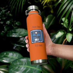 Könnte beinhalten: Orangefarbene Edelstahl-Wasserflasche mit silbernem Deckel und Griff. Die Flasche zeigt eine blau-weiße Grafik eines 3D-Druckers mit dem Text "WORK HARD" und "PLA HARD".