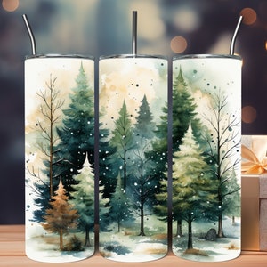 Pode incluir: Três copos de aço inoxidável com um design de aquarela de uma floresta nevada. O design apresenta árvores verdes e marrons com neve branca caindo.