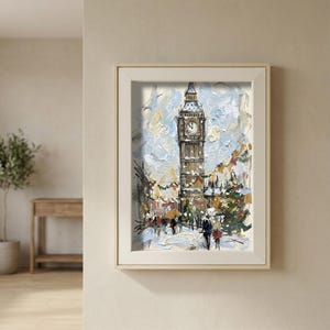 Pode incluir: Pintura a óleo da Torre Elizabeth, também conhecida como Big Ben, em Londres. A obra retrata uma cena de inverno com neve com figuras caminhando por uma rua. A torre é marrom com um mostrador de relógio, e o céu é uma mistura de azul e branco. A pintura é emoldurada.