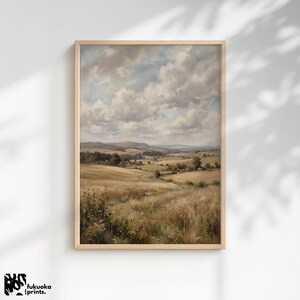 Puede incluir: Una pintura de paisaje enmarcada que representa una escena rural serena. La obra de arte presenta colinas onduladas, campos de hierba dorada y un camino sinuoso bajo un cielo nublado. La pintura está en un marco de madera.