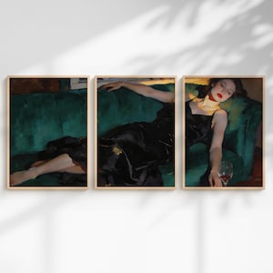 Pode incluir: Um tríptico de impressões de arte emolduradas. Cada impressão retrata uma pessoa em um vestido preto reclinada em um sofá de veludo verde. A arte tem uma estética vintage com foco na luz e sombra.