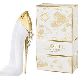May include: A white and gold perfume bottle shaped like a high heel, with a snowflake design. The box next to it is white with gold accents and the words "GOOD GIRL CAROLINA HERRERA NEW YORK SPARKLING ICE".