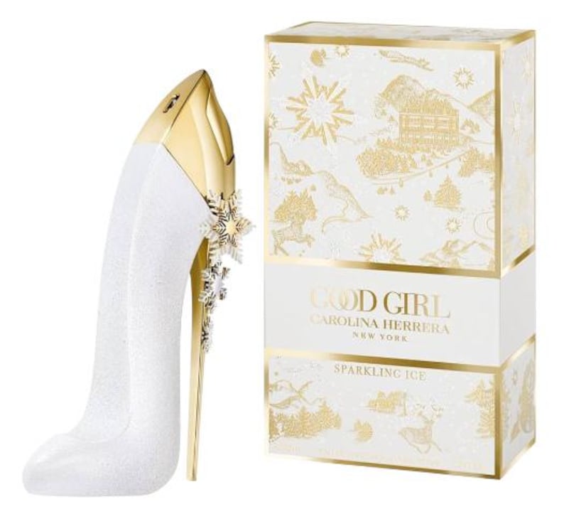 May include: A white and gold perfume bottle shaped like a high heel, with a snowflake design. The box next to it is white with gold accents and the words "GOOD GIRL CAROLINA HERRERA NEW YORK SPARKLING ICE".