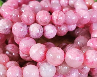 May include: Close-up of a bracelet made of pink gemstone beads. The beads are round and vary in shades of pink, from light to deep rose. The bracelet is strung on a pink elastic cord, creating a continuous loop.