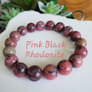 Puede incluir: Pulsera de piedras preciosas de rodonita rosa y negra. La pulsera est&aacute; hecha de cuentas redondas y tiene un acabado natural y pulido.